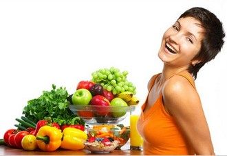 Young healthy woman laughing with fruits and vegetables.